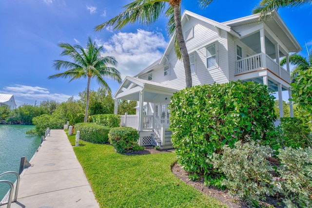 view of property exterior featuring a lawn, a dock, and a water view