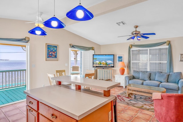 tiled living room with lofted ceiling, ceiling fan, and a water view