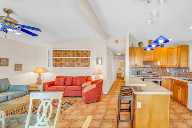 kitchen with lofted ceiling, sink, decorative light fixtures, appliances with stainless steel finishes, and a kitchen breakfast bar