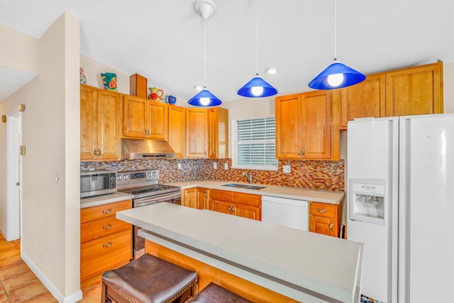 kitchen featuring appliances with stainless steel finishes, decorative light fixtures, sink, a breakfast bar area, and backsplash