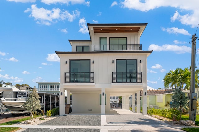 view of front of home featuring a carport, driveway, board and batten siding, and a balcony