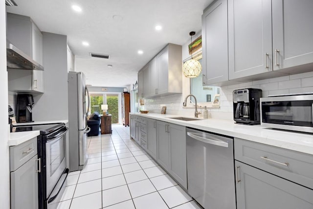 kitchen featuring gray cabinets, appliances with stainless steel finishes, decorative light fixtures, sink, and wall chimney exhaust hood