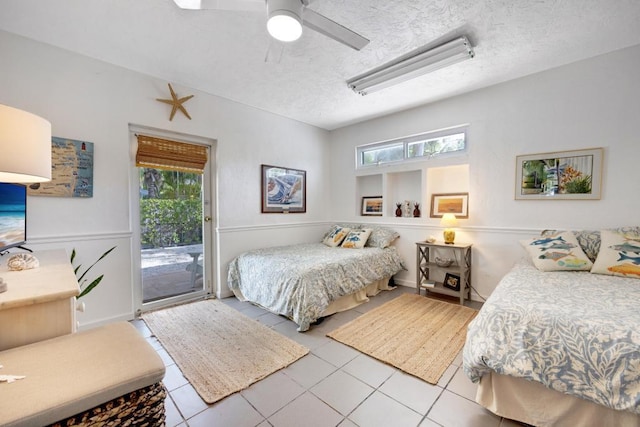 tiled bedroom with ceiling fan, a textured ceiling, multiple windows, and access to outside