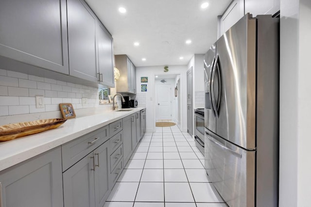 kitchen with gray cabinets, light tile patterned flooring, sink, backsplash, and stainless steel appliances