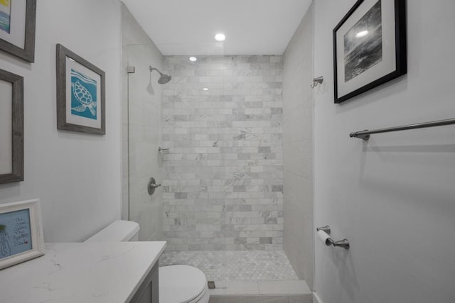 bathroom with vanity, tiled shower, and toilet