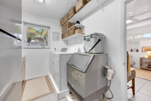 laundry area with separate washer and dryer, a healthy amount of sunlight, and light tile patterned floors