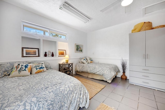 tiled bedroom featuring ceiling fan and a textured ceiling