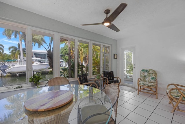 sunroom / solarium featuring ceiling fan and a water view