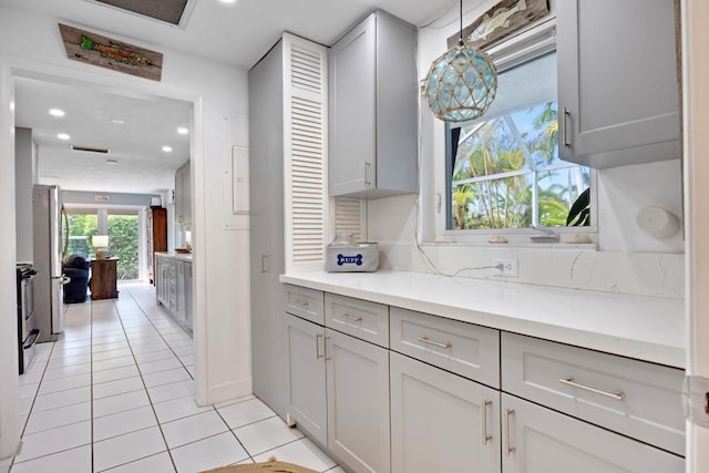 kitchen featuring stainless steel appliances, pendant lighting, gray cabinetry, and light tile patterned floors