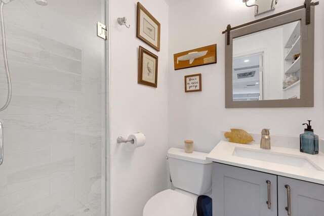 bathroom with vanity, a shower with door, and toilet