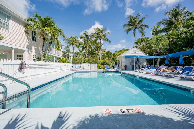 community pool featuring a patio area, fence, and an outbuilding