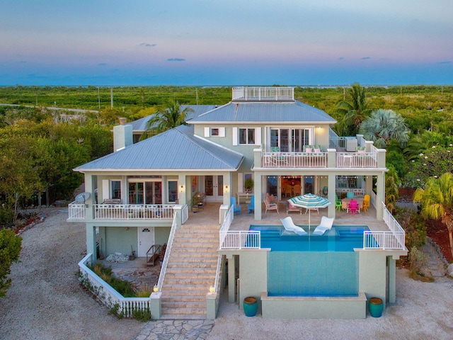 4500 Filer Cove Rd, Big Torch, FL 33042 - back of house at dusk with a balcony, an outdoor pool, a patio, and metal roof