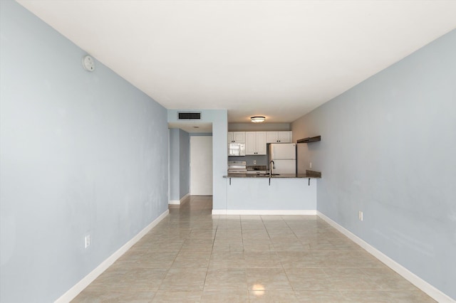 unfurnished living room featuring a sink and baseboards