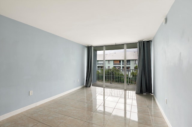 spare room featuring expansive windows, tile patterned floors, and baseboards