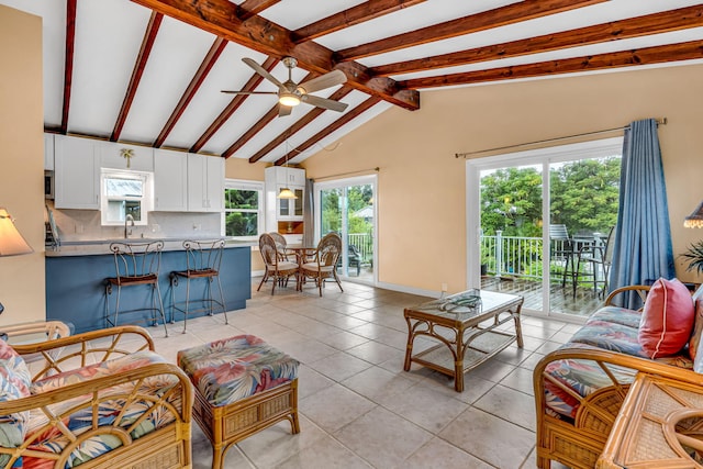 living room featuring light tile patterned floors, lofted ceiling with beams, sink, and ceiling fan