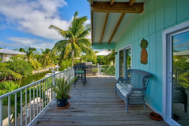 wooden terrace with grilling area and a water view