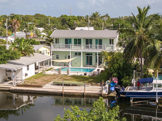 rear view of property with a water view, a patio, and a balcony