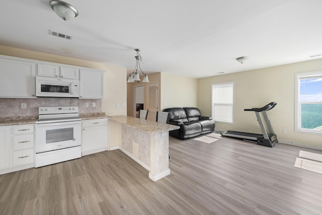 kitchen featuring white appliances, white cabinetry, a healthy amount of sunlight, decorative backsplash, and kitchen peninsula