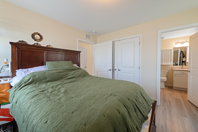 bedroom featuring sink, light hardwood / wood-style flooring, a closet, and ensuite bathroom