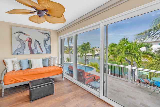 sunroom with ceiling fan and a water view