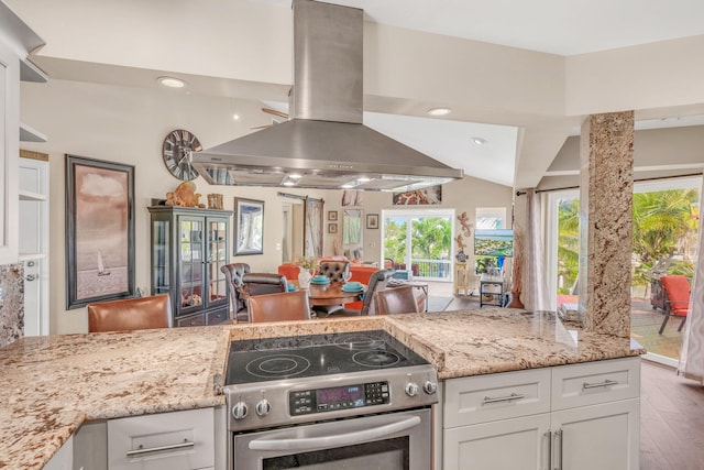 kitchen with electric range, light stone countertops, white cabinets, and island exhaust hood