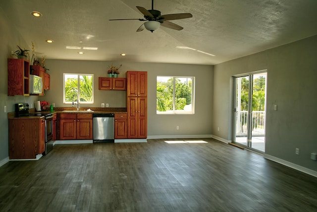 kitchen featuring appliances with stainless steel finishes, a wealth of natural light, a textured ceiling, and dark hardwood / wood-style flooring