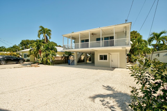 coastal home with ceiling fan, a carport, and a balcony