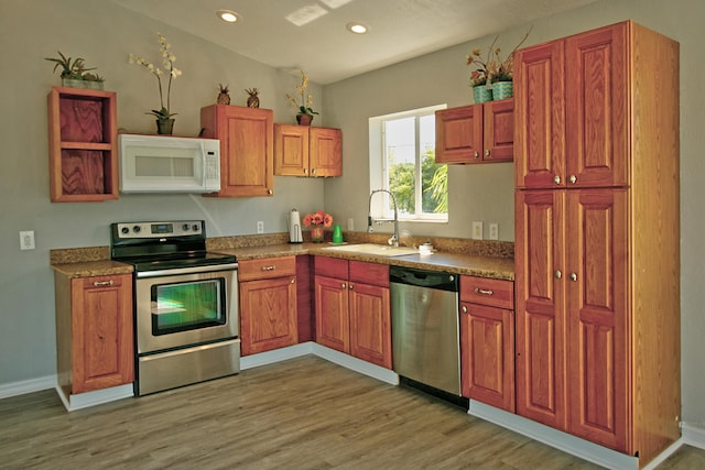 kitchen with stainless steel appliances, sink, and light hardwood / wood-style floors