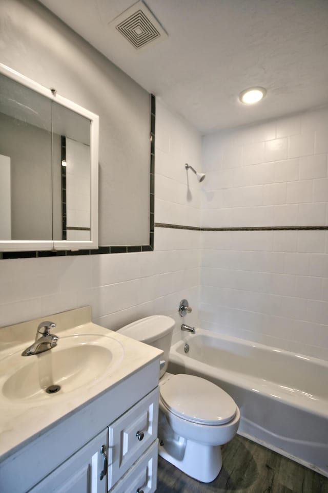 full bathroom with tiled shower / bath, wood-type flooring, vanity, and toilet