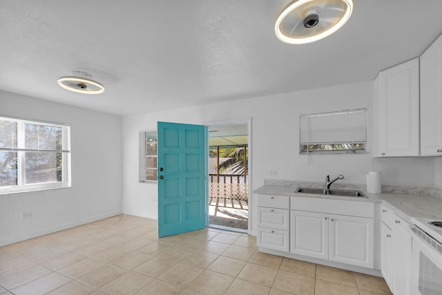 kitchen featuring white electric stove, light tile patterned flooring, a sink, white cabinets, and light stone countertops