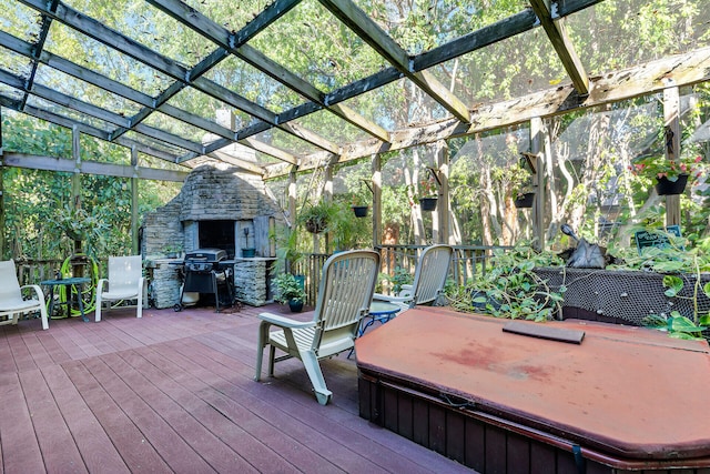 wooden deck with a covered hot tub, an outdoor stone fireplace, a grill, and a pergola