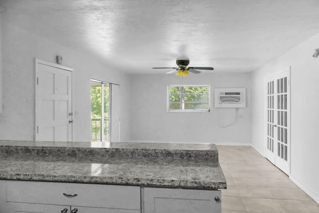 kitchen with stone counters, a wall unit AC, plenty of natural light, and ceiling fan