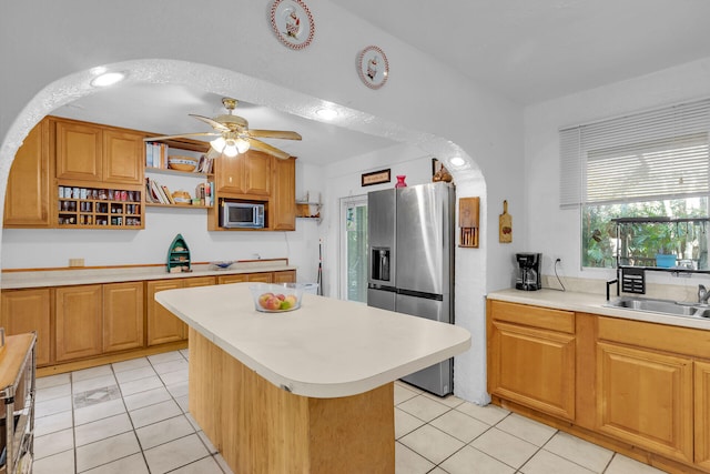 kitchen featuring a ceiling fan, a center island, stainless steel appliances, light countertops, and light tile patterned flooring