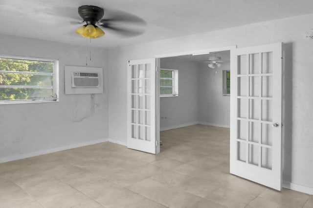 empty room featuring french doors, a wall unit AC, ceiling fan, and baseboards