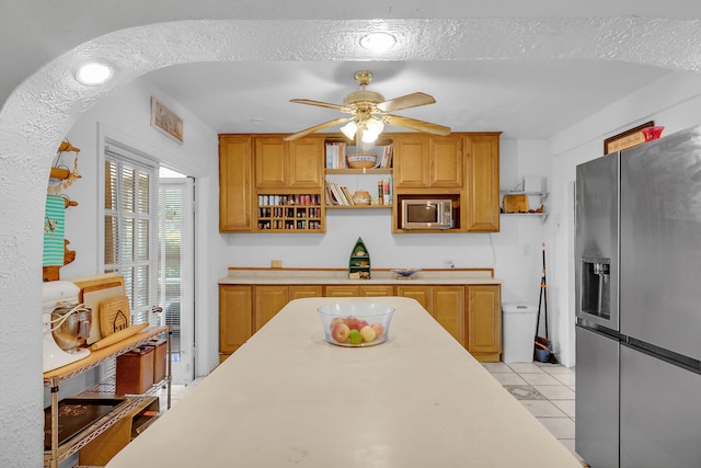 kitchen featuring light tile patterned floors, appliances with stainless steel finishes, light countertops, and a ceiling fan