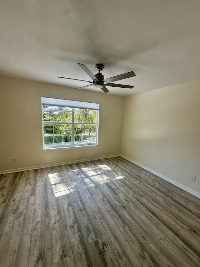 empty room with ceiling fan, baseboards, and wood finished floors