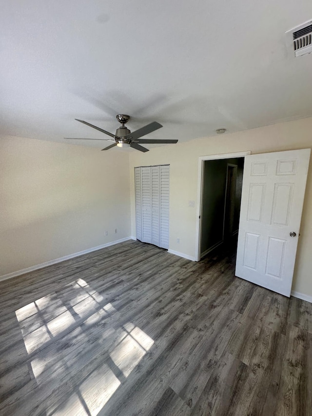 unfurnished bedroom with dark wood-type flooring, visible vents, and baseboards