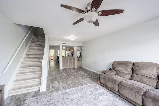 living area with stairs, visible vents, baseboards, and wood finished floors