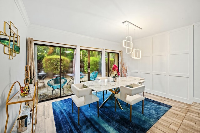 dining space featuring a chandelier, ornamental molding, wood finish floors, and a decorative wall