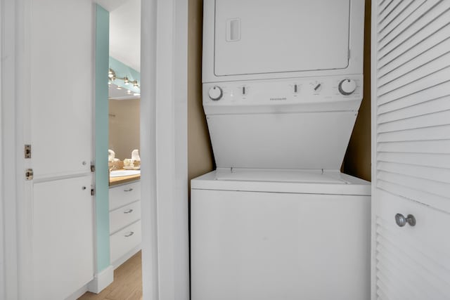 clothes washing area featuring light wood-type flooring and stacked washer / dryer