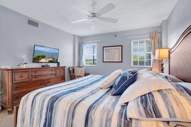 carpeted bedroom featuring ceiling fan, multiple windows, and a textured ceiling