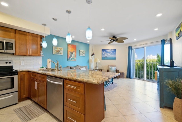 kitchen with stainless steel appliances, a peninsula, a sink, decorative backsplash, and brown cabinetry