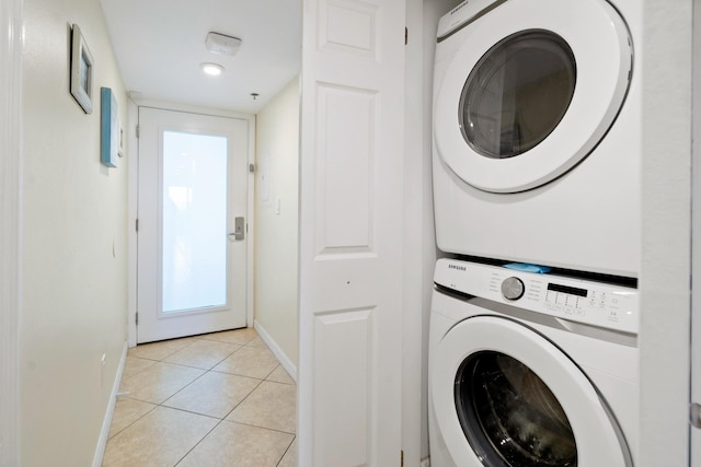 laundry room with laundry area, baseboards, stacked washing maching and dryer, and light tile patterned floors