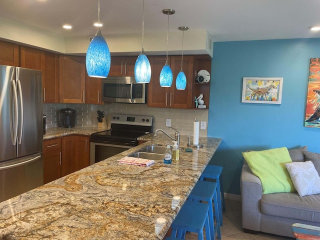 kitchen featuring light stone countertops, backsplash, stainless steel appliances, and a sink