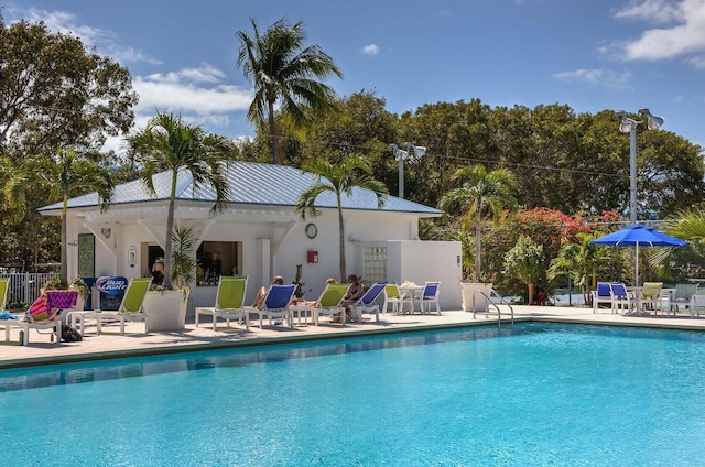 pool featuring a patio, an outdoor structure, and fence