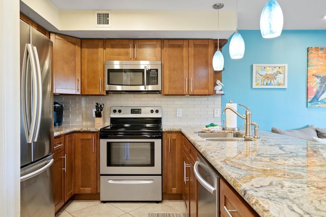 kitchen featuring light tile patterned flooring, sink, decorative light fixtures, appliances with stainless steel finishes, and light stone countertops