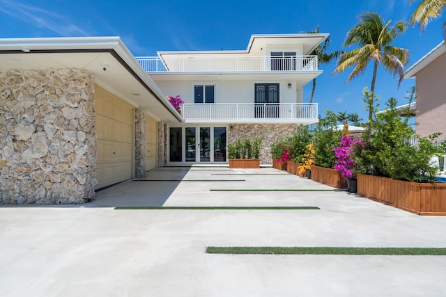 rear view of property with french doors, a balcony, and a garage