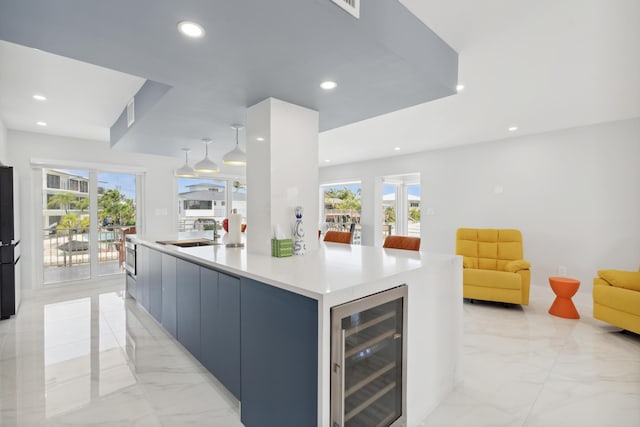 kitchen with a large island, sink, plenty of natural light, and beverage cooler