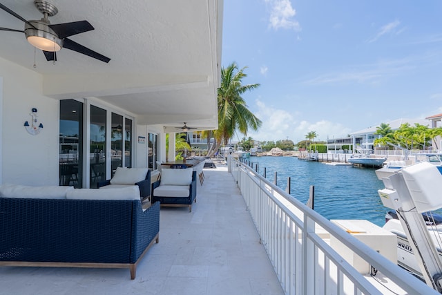 view of patio featuring a balcony, outdoor lounge area, ceiling fan, and a water view