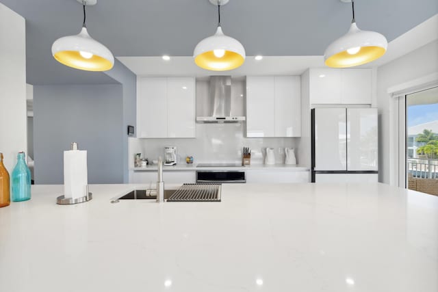 kitchen featuring wall chimney range hood, decorative light fixtures, and white fridge